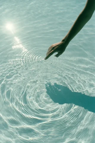 Hand Shadow on Pool Ripples — Midjourney v6 AI Prompt: a minimalist conceptual photograph of a female hand shadow touching the center o...