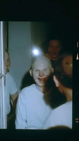 Analog Horror Home Video Smile — Midjourney v6 AI Prompt: something wearing a person's skin slightly wrong, seams at the jaw, smiling into...