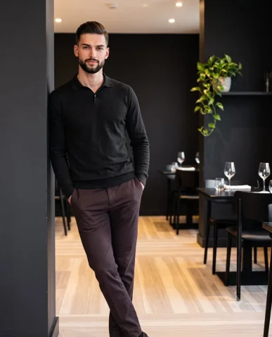 Confident man in charcoal black leans casually against a column — Nano Banana 2 AI Prompt: A confident adult male model stands full-scale on the left, deliberately posed f...