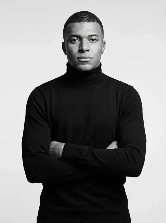 Confident man in black turtleneck stares directly at camera