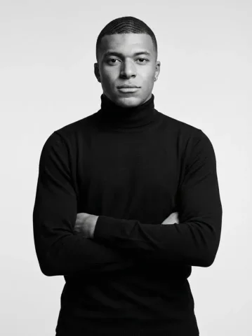 Confident man in black turtleneck stares directly at camera — Nano Banana 2 AI Prompt: Ultra-realistic black-and-white studio portrait of a confident athletic man stan...