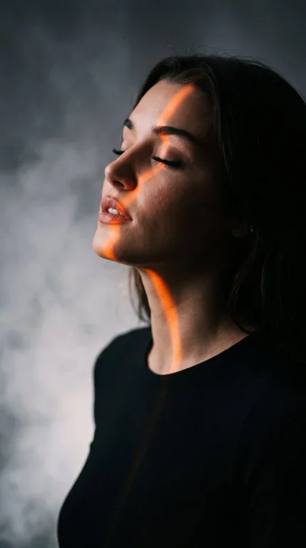 A serene side profile woman glows in orange chiaroscuro light