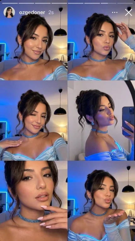 Young woman in blue glowing dress takes playful selfies at night