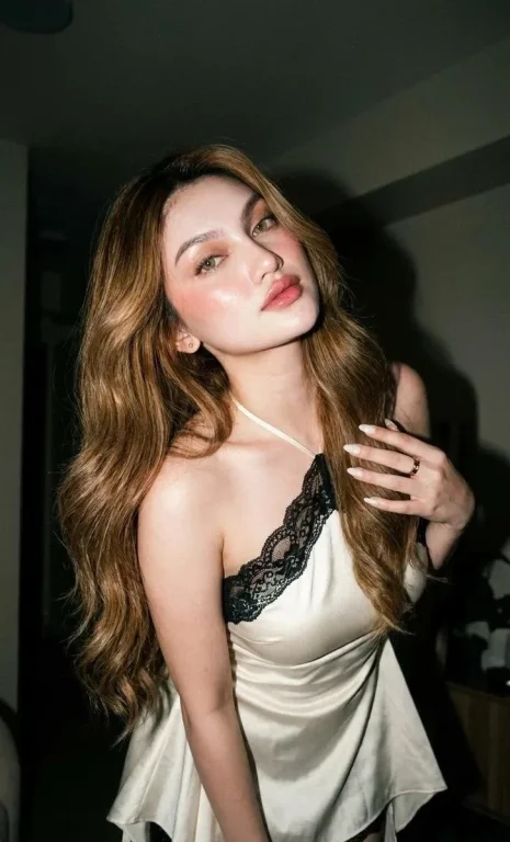 A glamorous woman sweeps her caramel hair back under a flash
