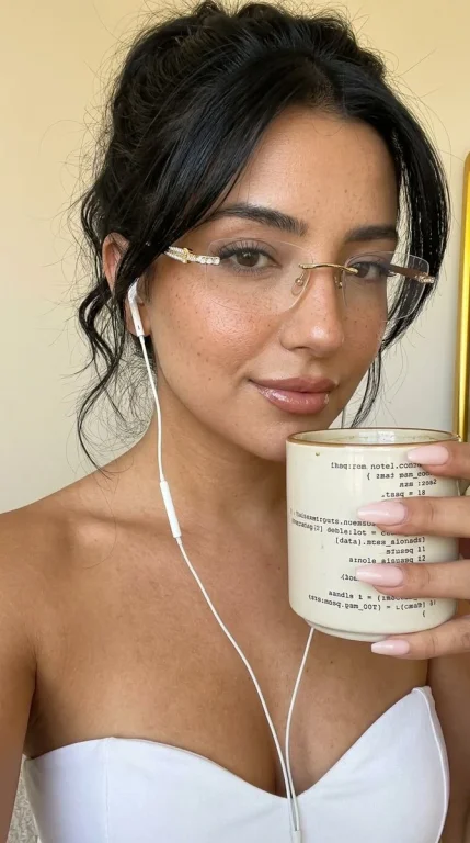 Woman with crystal-studded glasses holds glowing code mug