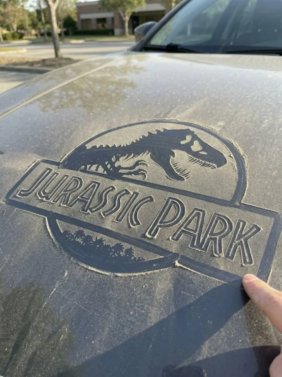 Finger-Traced Logo on Dusty Car Hood