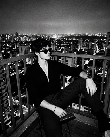 Noir Portrait of a Man on a City Balcony in High Contrast Black and White — Nano Banana 2 AI Prompt: Create a portrait without changing the facial features. A black and white artist...