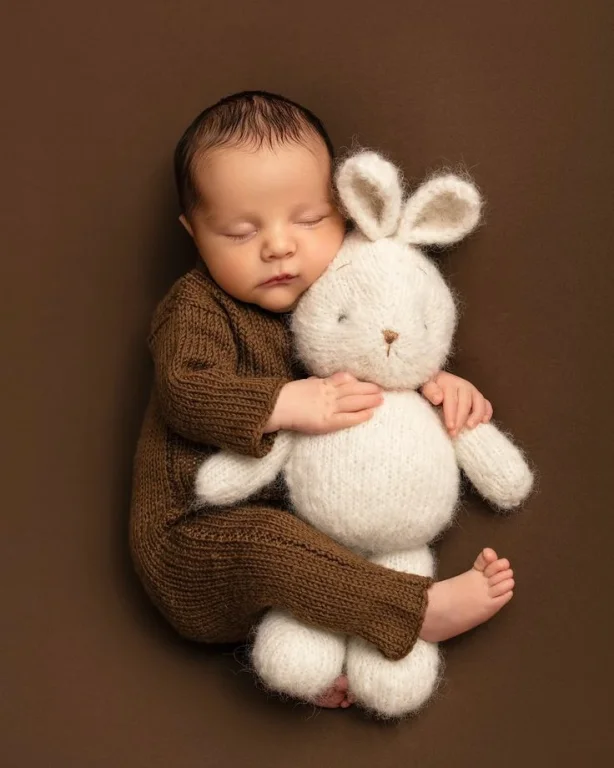 A Newborn Baby, With Dark Hair, Sleeping Deeply On A Rich, Solid