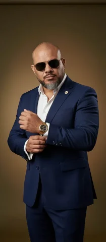A Confident Man In A Navy Blue Tailored Suit With A White Shirt, — Nano Banana Pro AI Prompt: A confident man in a navy blue tailored suit with a white shirt, no tie, adjusti...