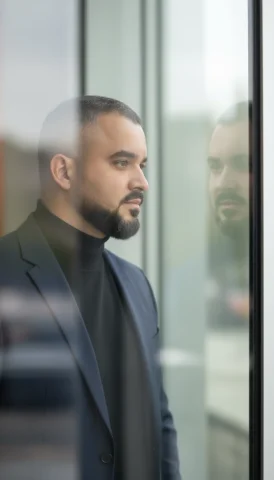 A Cinematic Close-Up Portrait Of A Stylish Individual Standing By — Nano Banana Pro AI Prompt: A cinematic close-up portrait of a stylish individual standing by a large glass...