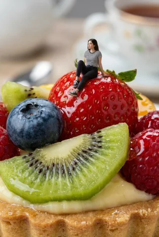 A Tiny World of Sugary Wonders — Nano Banana 2 AI Prompt: Surreal macro photography capturing a miniature female figure with the uploaded...