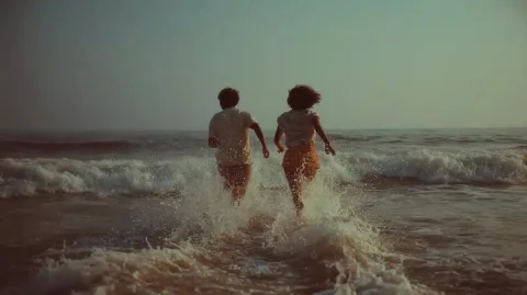 Cinematic Couple at Sunset — Midjourney v6 AI Prompt: close portrait frontal shot of a couple running into the water of beach, portuga...