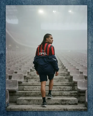 Foggy Stadium Retro Football Kit 6 — Nano Banana AI Prompt: The photograph depicts: Three-quarter back view of a young athletic man with lon...