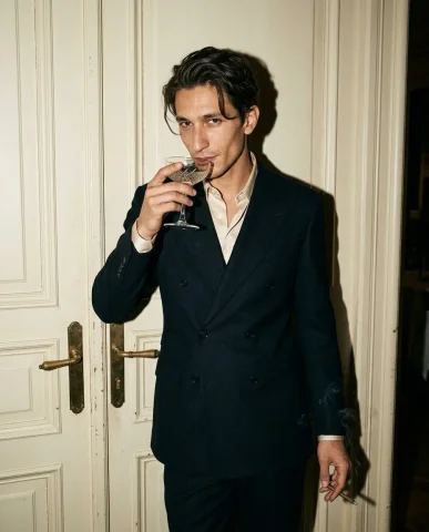 Flash Portrait Against Cream Doors 2 — Nano Banana AI Prompt: He wears a sharply tailored deep midnight-navy double-breasted suit with wide pe...