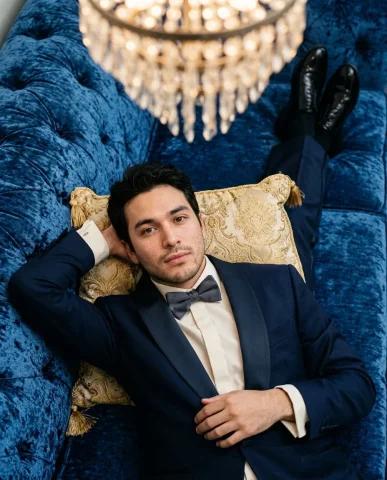 Tuxedo on Sapphire Velvet Sofa 5 — Nano Banana AI Prompt: Close-up editorial portrait in an ornate neoclassical interior. A handsome young...