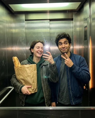 Accidental Elevator Selfie with a Friend 2 — Nano Banana AI Prompt: Phone selfie in the scratched stainless-steel elevator with both subjects mid-la...