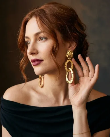 Valentino Style Gold Statement Earrings Portrait 5 — Nano Banana AI Prompt: Her fingers — index and middle — delicately hold one of the cascading hammered o...