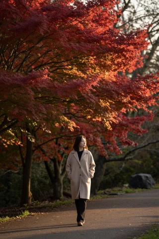 A Woman Walks Alone Along A Path Beneath A Canopy Of Vivid R... — Stable Diffusion AI Prompt: A woman walks alone along a path beneath a canopy of vivid red maple trees, hand...