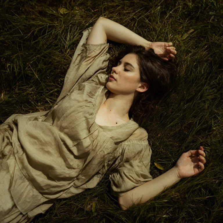 A Woman Wearing A Dress Is Laying In Grass.