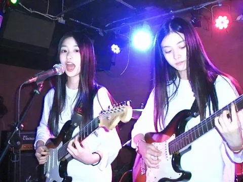 2 Chinese 25 Years Old Girls Playing On Electric Guitars And... — Stable Diffusion AI Prompt: 2 chinese 25 years old girls playing on electric guitars and one of them singing...