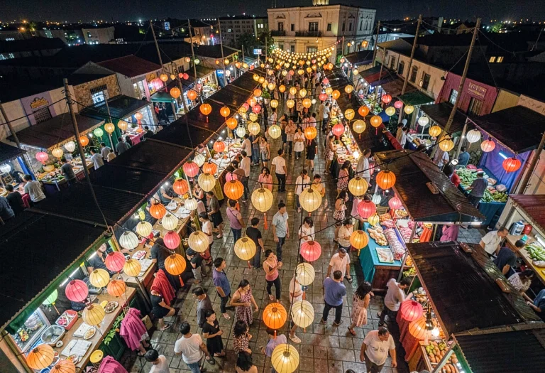 A Bustling Night Bazaar Strung With Paper Lamps, Physically...
