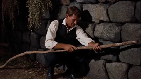 Tmmchn1960, A Man In A White Shirt And Dark Vest Crouches Ag... — Stable Diffusion AI Prompt: tmmchn1960, A man in a white shirt and dark vest crouches against a rough stone...