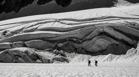 Two Tiny Silhouetted Hikers Traverse A Vast, Undulating Expa... — Stable Diffusion AI Prompt: Two tiny silhouetted hikers traverse a vast, undulating expanse of snow in a sta...