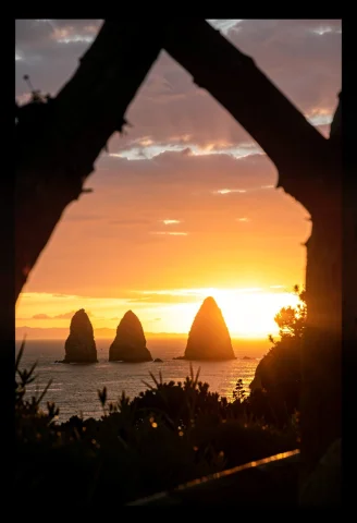 Sea Stacks Silhouetted Against A Burning Sunset, Harsh Midda... — Stable Diffusion AI Prompt: sea stacks silhouetted against a burning sunset, harsh midday sun, framed by for...