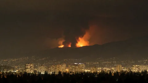 Nighttime Cityscape Dominated By Distant Mountain Wildfires,... — Stable Diffusion AI Prompt: Nighttime cityscape dominated by distant mountain wildfires, dense grid of glowi...