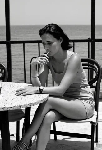 Alone At A Table For Two On A Terrace Facing The Sea, She Ch... — SDXL AI Prompt: Alone at a table for two on a terrace facing the sea, she checks her watch with...