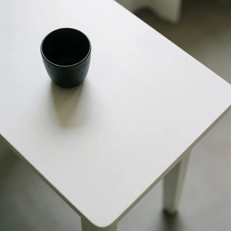 An Overhead View Of A Calm White Tabletop With A Single Blac...