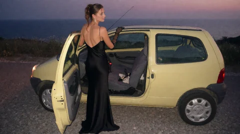 Tw1car A Woman In A Floor-length Black Satin Evening Gown St... — Stable Diffusion AI Prompt: tw1car A woman in a floor-length black satin evening gown stands beside a pale-y...