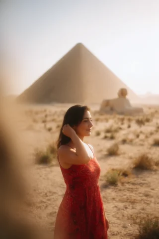 A Woman In A Red Patterned Dress Poses In A Sunlit Desert, T... — Stable Diffusion AI Prompt: A woman in a red patterned dress poses in a sunlit desert, touching her dark hai...