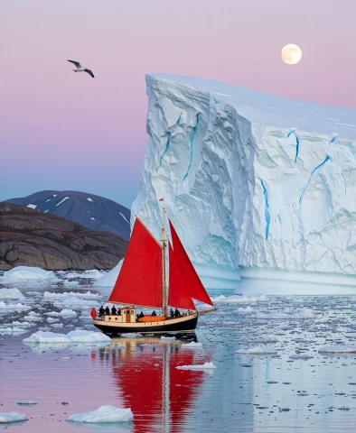 A Small Red-sailed Ketch Anchored Among Floating Ice Beneath... — Stable Diffusion AI Prompt: A small red-sailed ketch anchored among floating ice beneath a towering iceberg...